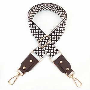 Detail of jacquard embroidered bag strap with premium leather ends and gold metal buckles