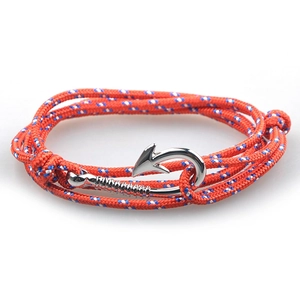 Close-up of red woven rope bracelet with silver fish hook clasp on white background
