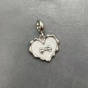 Dettaglio ravvicinato di un ciondolo a cuore in argento con fiocco su trama in pelle