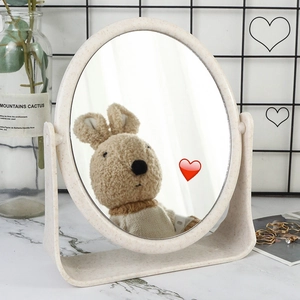 Beige oval desktop makeup mirror with U-shaped stand on marble table in a cozy home setting