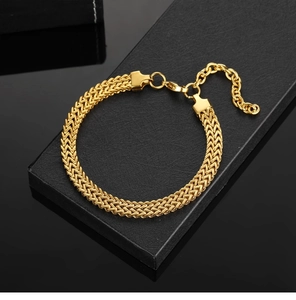 Detailed close-up of a golden punk braided Cuban chain bracelet on a black gift box