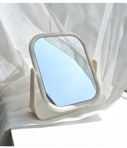 Detail of a beige desktop makeup mirror with adjustable rotation on a bright white table