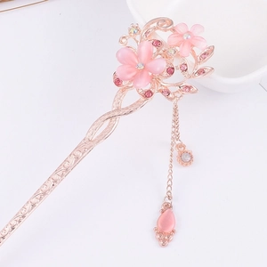 Macro detail of rose gold hair pin featuring pink cat eye flowers and sparkling tassels