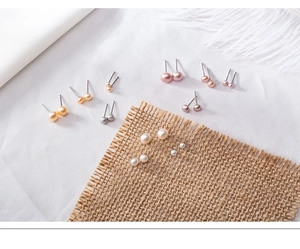 Selection of natural freshwater pearl earrings in various colors and sizes on white linen