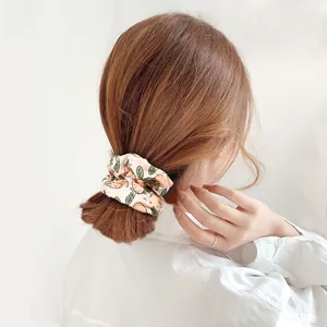 Detailed back view of a pink floral scrunchie with orange patterns on a ponytail hair