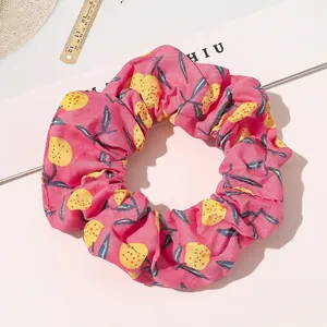 Detailed view of pink floral fabric scrunchie with yellow fruit pattern and elastic band