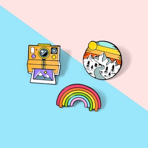Three-piece set of colorful enamel pins featuring a retro camera, mountain landscape, and rainbow