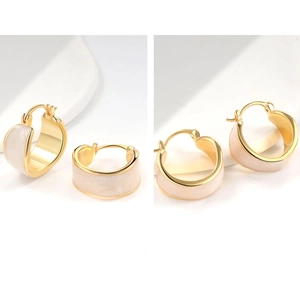 Macro view of C-shaped 18k gold plated hoop earrings with white marble enamel inlay