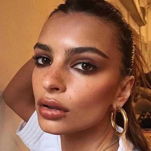 Close-up of model wearing large polished gold hoop earrings with minimalist metal finish