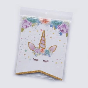 Close-up of unicorn birthday banner card with gold glitter and floral details in polybag