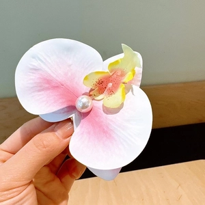 Detailed close-up of a realistic pink orchid hair clip with faux pearl center and petals