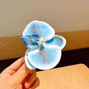 Detail of blue and white gradient orchid hair clip with a pearl center for women