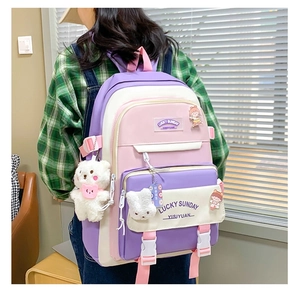 Detail view of purple and pink school backpack with cute plush bear and rabbit pendants