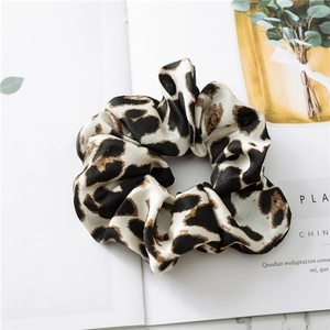 Close-up of leopard print satin hair scrunchie on a fashion magazine with silk texture