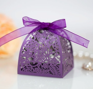 Detail of purple laser-cut wedding candy box with rose hollow pattern and silk ribbon