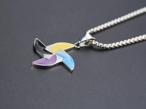 Macro shot of silver windmill necklace pendant with colorful black yellow purple blue enamel