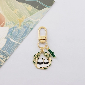 Close-up of golden panda keychain with green bamboo ring and panda couple details