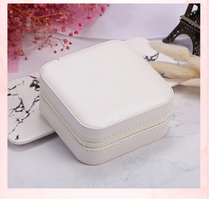 Portable white velvet jewelry box with zipper on a marble base with pink floral decor