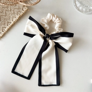 Detail of elegant black and white bow scrunchie with long ribbons and satin texture