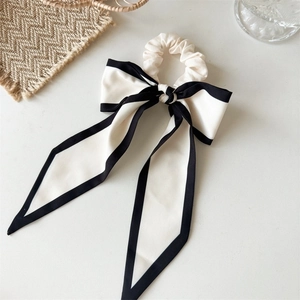 Close-up of the elegant white satin bow hair scrunchie with black contrasting piping edges