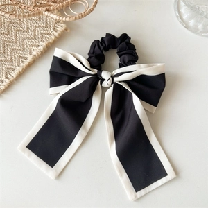 Detail view of a black bow scrunchie with white trim and long elegant streamers