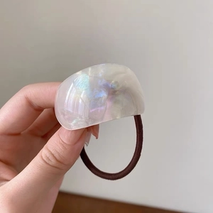 Macro shot of minimalist brown hair tie with a shimmering acetate hemisphere charm