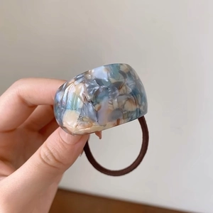 Macro detail of curved acetate hair tie with elegant blue and grey marble texture
