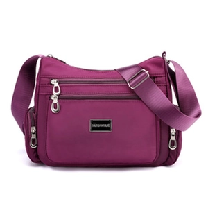 Detail of purple nylon crossbody bag featuring multiple silver zippers and adjustable strap