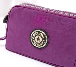 Detail of purple nylon cosmetic bag showing triple-zipper design and textured material