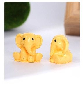Detail of yellow resin elephant figurines on moss for miniature landscape decor
