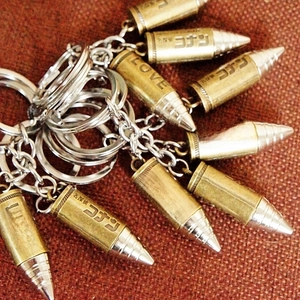Detailed close-up of bullet-shaped metal keychains featuring engraved lettering