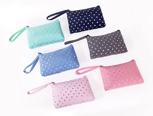 Selection of portable fabric makeup bags with gold polka dot patterns in six vibrant colors