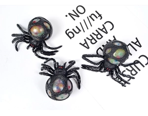 Detail of black spider stress ball filled with colorful water beads on decorative paper