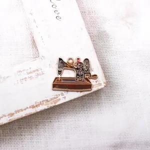 Close-up of retro enamel sewing machine pendant charm on a beige rustic backdrop