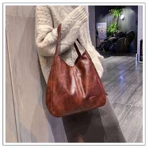 Detail of vintage brown leather tote bag with embossed logo and cross stitching decoration