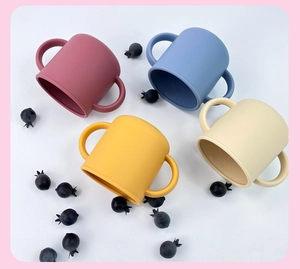 Top view of baby silicone training cups in four colors with dual handles and scale lines