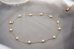 Detail of adjustable gold pearl necklace on mesh fabric with elegant glass decor