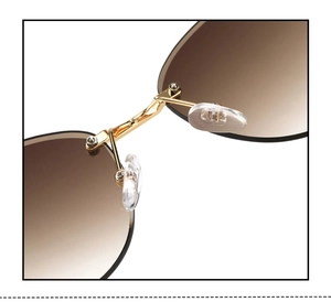 Detail of rimless oval sunglasses showing gold metal bridge and clear silicone nose pads