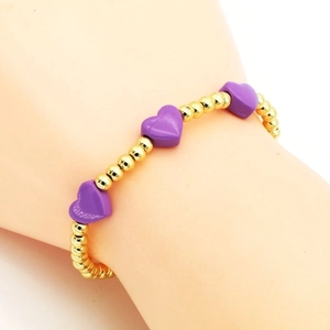 Minimalist gold beaded bracelet with purple enamel hearts on female wrist