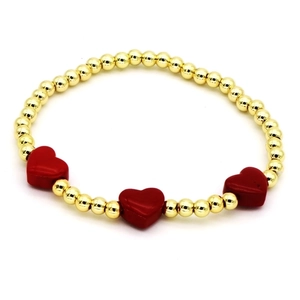 Minimalist gold beaded bracelet featuring three vibrant red enamel heart-shaped charms