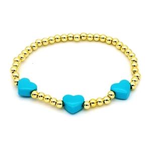 Detailed shot of golden beaded bracelet with three sky blue enamel heart charms