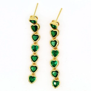 Macro shot of long gold earrings with cascading green heart-shaped gemstones