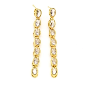 Macro shot of long gold earrings featuring seven sparkling oval-cut zircon gemstones