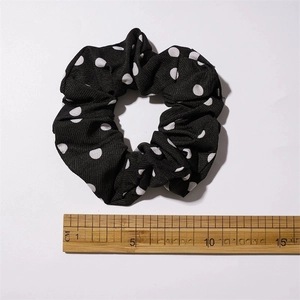 Detailed view of black polka dot fabric scrunchie with 10cm diameter measurement guide