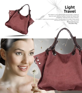 Detail of burgundy canvas tote showing brown handle with silver metal ring and rivets