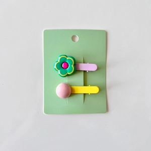 Detail of colorful floral and bead hair clips for girls set on a green card