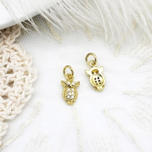 Detailed close-up of golden owl charm with micro-pave white zircon stones and metal texture
