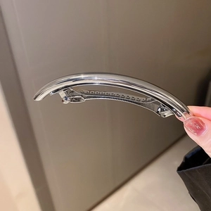 Detail of minimalist curved silver metal hair clip with a high-shine polished finish