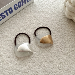 Minimalist hair ties with metallic gold and silver accents on elegant beige fabric