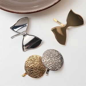 Macro detail of metallic hair clips with hammered texture and smooth bow designs